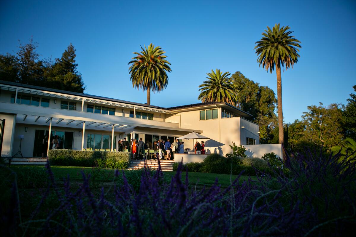 People stand on the patio of a two-story home.