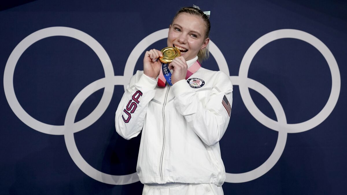 Jade Carey holds her gold medal up to her mouth.