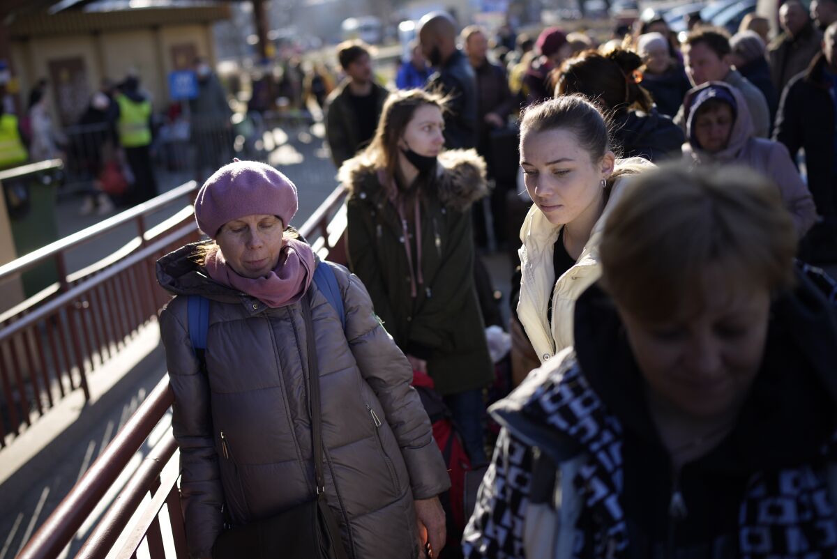 People wait in a line to board a train leaving for Lviv in Ukraine at the train station in Przemysl, Poland, Monday, March 14, 2022. While tens of thousands of people have fled Ukraine every day since Russia's invasion, a small but growing number are heading in the other direction. At first they were foreign volunteers, Ukrainian expatriate men heading to fight and people delivering aid. But increasingly, women are also heading back. (AP Photo/Daniel Cole)