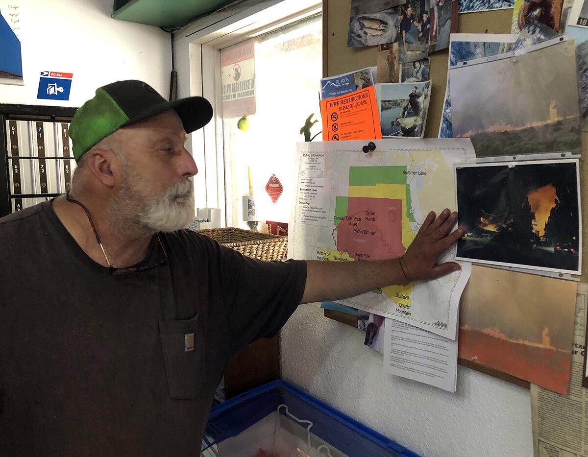 Dale Chiono surveys photos of previous wildfires posted in his Summer Lake Store.