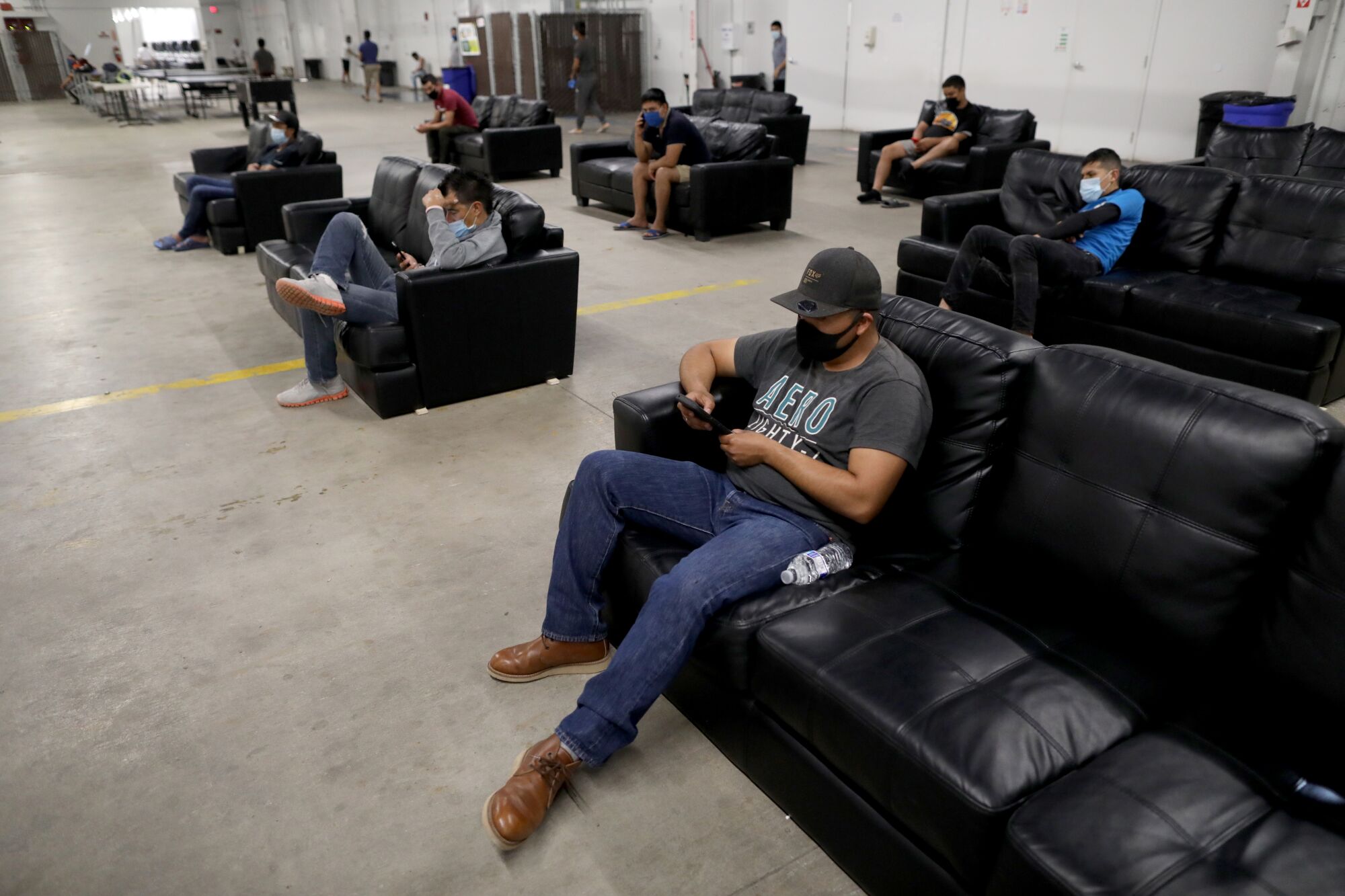 After finishing work, farmworkers relax in the living space practicing social distancing