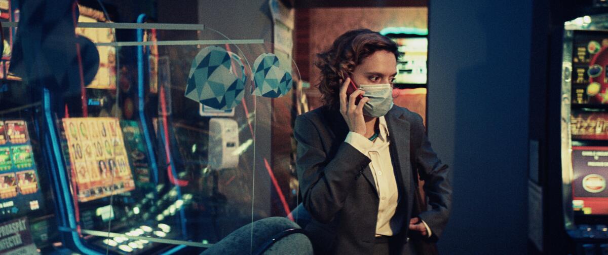 A woman wearing a surgical mask talks on the phone.
