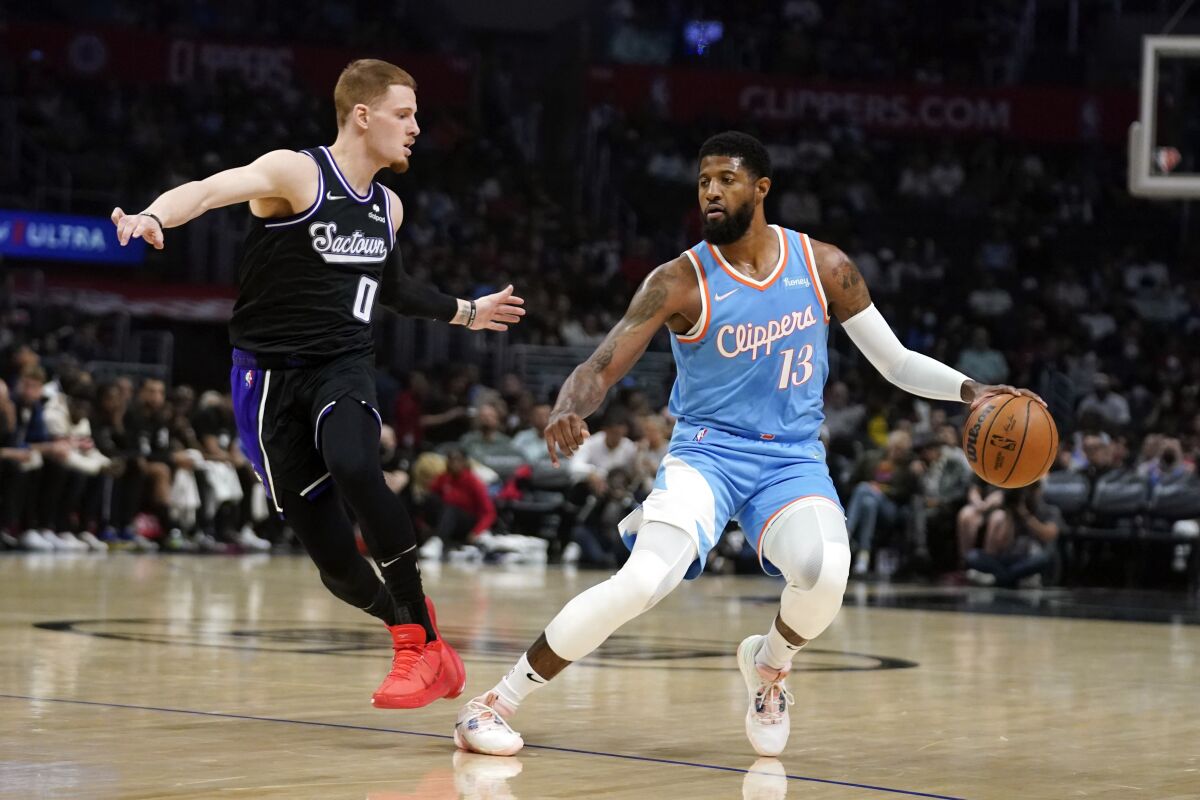 Los Angeles Clippers guard Paul George (13) is defended by Sacramento Kings guard Donte DiVincenzo (0) during the first half of an NBA basketball game Saturday, April 9, 2022, in Los Angeles. (AP Photo/Marcio Jose Sanchez)