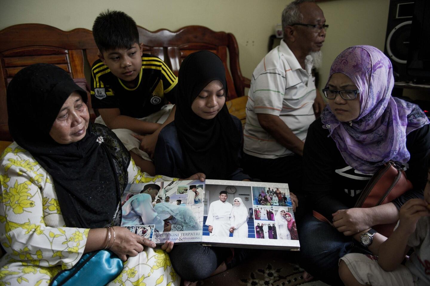 Family members look at a wedding album of Norliakmar Hamid and Razahan Zamani, passengers on a missing Malaysia Airlines Boeing 777-200 plane in Kuala Lumpur.