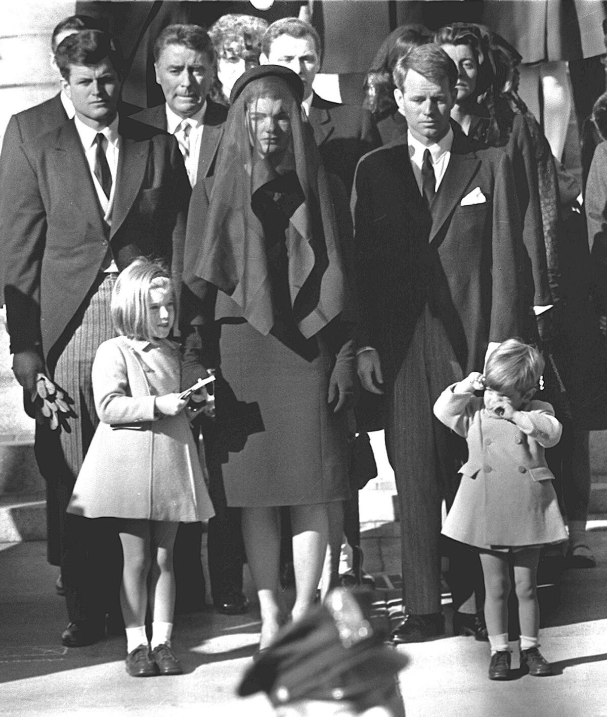 Jacqueline Kennedy stands with her two children, Caroline Kennedy and John F. Kennedy Jr., and brothers-in-law Ted Kennedy, back left, and Robert Kennedy, right, at the funeral of her husband, President John F. Kennedy, in Washington.