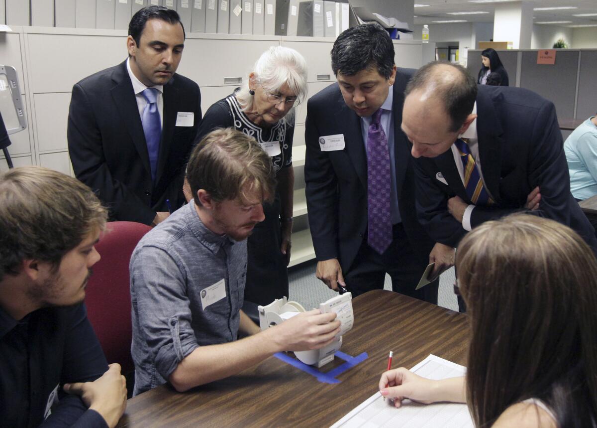 Observers watch Micah Kagler (seated, second from left) of the Kern County Elections Division read a vote from a ballot in the California controller race.