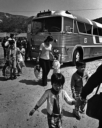 Vietnamese children dressed in new but mismatched clothes file off a Greyhound charter bus with their families at Camp Pendleton. They were first evacuated to Guam and then to Pendleton. Tens of thousands of South Vietnamese were brought here after the communist takeover and housed in big squad tents while sponsors were lined up to help them resettle in the U.S. See full story