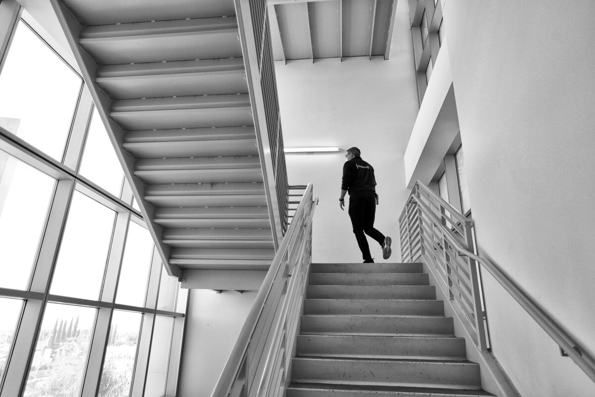 A man stands at the top of a metal staircase. 