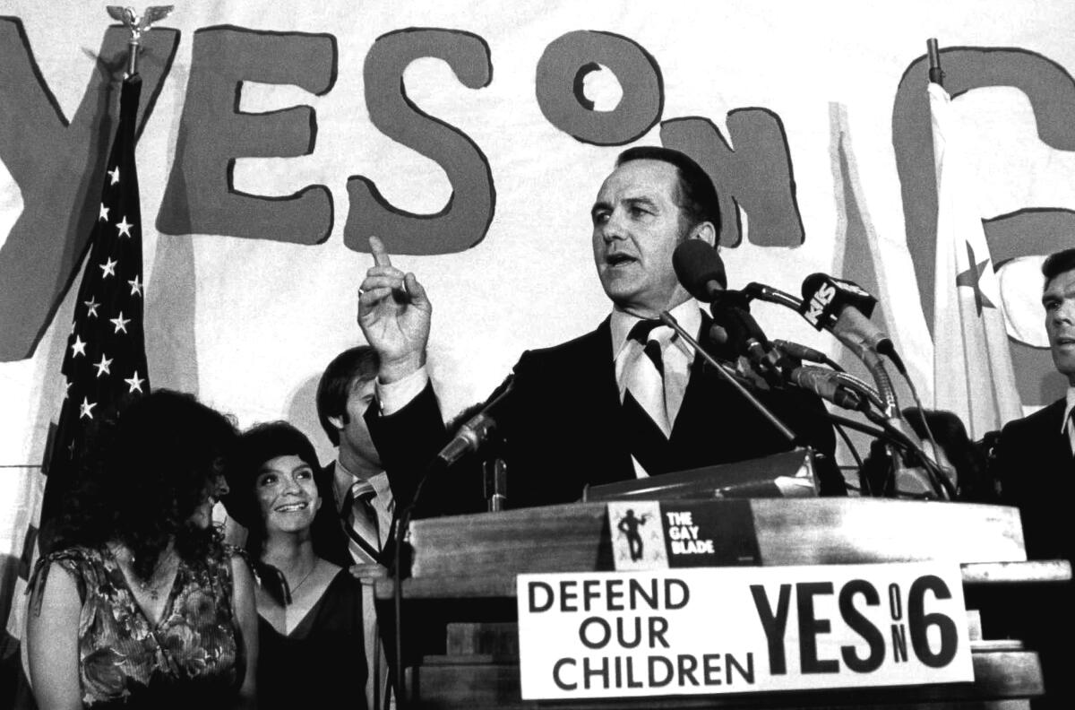 John V. Briggs speaks at a lectern with "Yes on 6" signage and supporters.