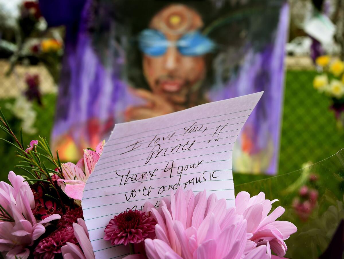 A Prince fan holds flowers outside the Paisley Park compound in Minneapolis on April 22, 2016. Prince died April 21, 2016.