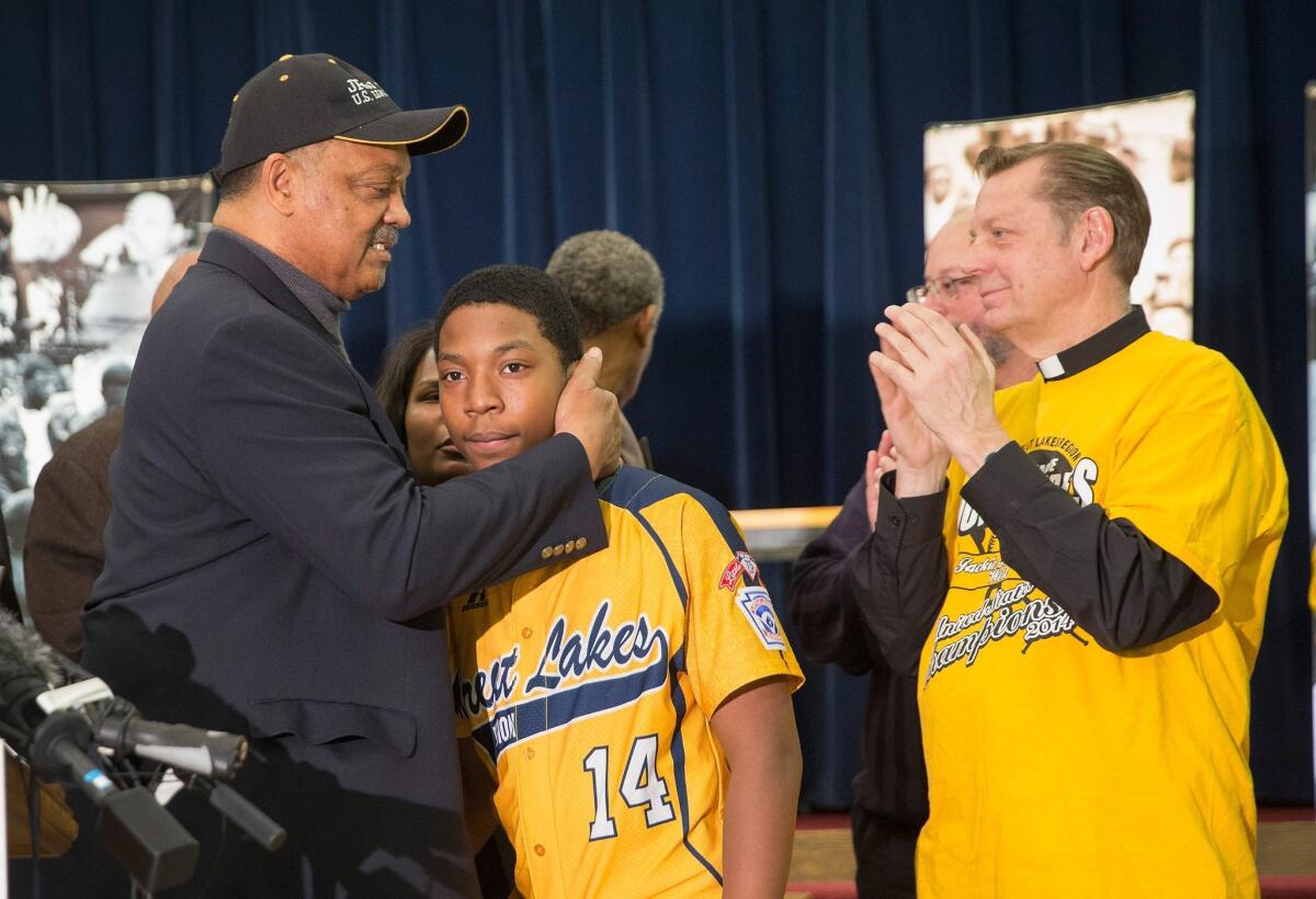 Brandon Green, a catcher and pitcher for the Jackie Robinson West Little League baseball team, is embraced by civil rights leader Rev. Jesse Jackson after a news conference on Wednesday.