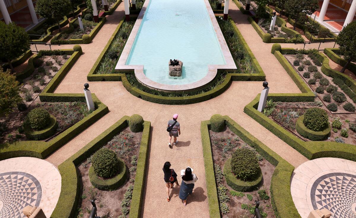 Os visitantes andam pelo motivo de Getty Villa em Pacific Palilides