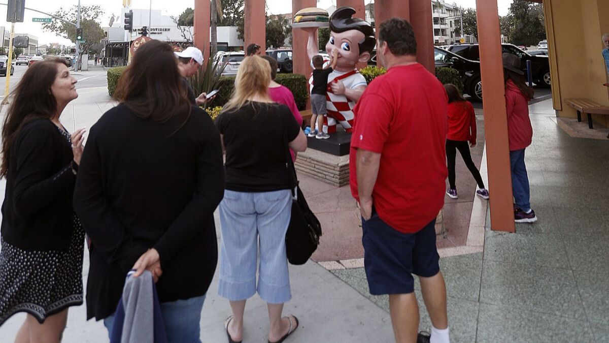 People gather around the Big Boy statue in front of the Bob's Big Boy restaurant to take photos on Tuesday. The restaurant is celebrating 70 years in Burbank.