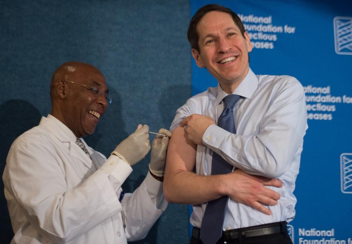Dr. Tom Frieden, right, director of the Centers for Disease Control and Prevention, demonstrates how easy it is to get a flu shot. This year's flu vaccines are a good match to the viruses now in circulation, a new CDC report says.