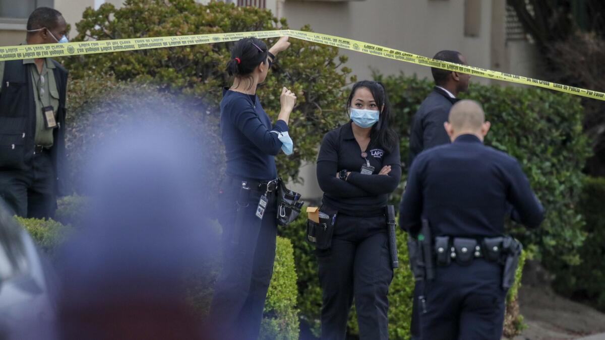 Investigators work at the scene after the bodies of three people were found in a home in the 3900 block of South Bronson Avenue in Leimert Park.