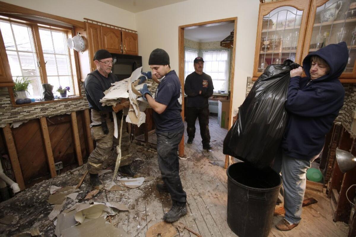 New Orleans firefighter Bruce Hurley Sr., left, and New York firefighter John Militano clear Sheetrock from a gutted kitchen as homeowner Colleen Dwyer, right, bags debris in her home flooded in Superstorm Sandy in the Belle Harbor section of Queens, N.Y., on Wednesday. Sandy, which hit the Northeast hard, was the reason jobless claims spiked