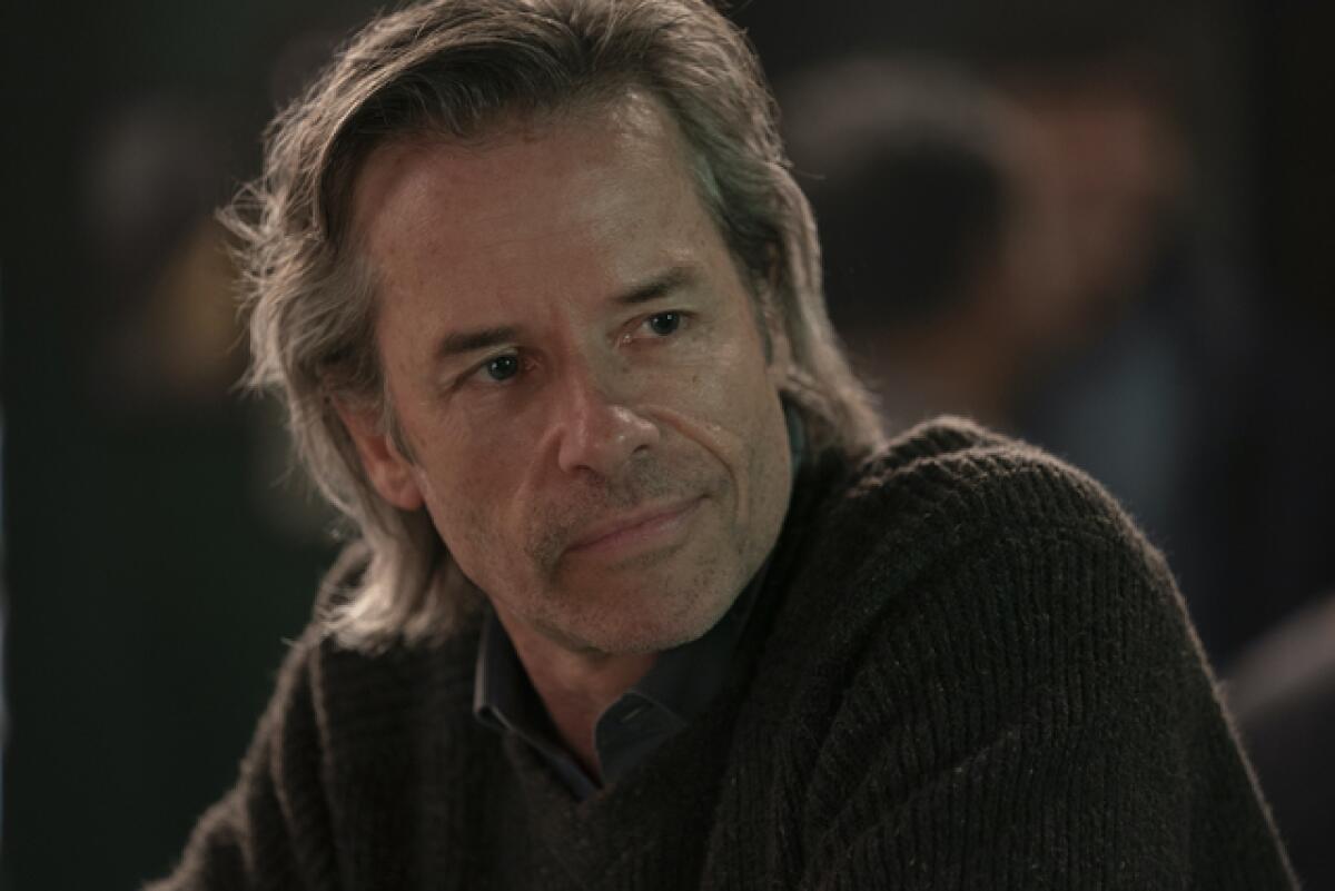 Guy Pearce in a brown sweater with long, graying hair