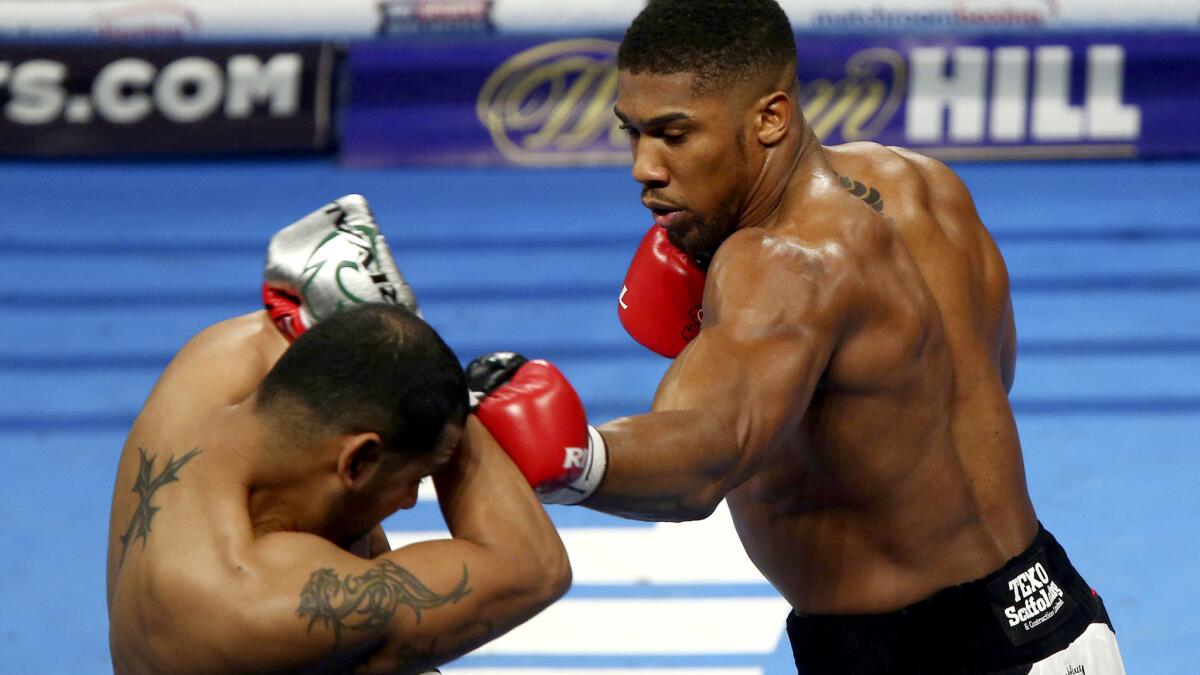IBF heavyweight champion Anthony Joshua, right, forces Eric Molina against the ropes with a flurry of punches during their bout on Dec. 10, 2016 in Manchester, England.