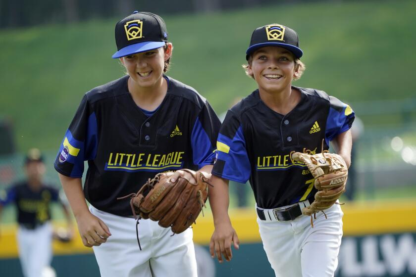 Torrance, Calif.'s Dominic Golia (18) and pitcher Xavier Navarro (7) smile as the run off the field after Navarro caught a line drive back to the mound off the bat of Hamilton, Ohio's Kaleb Harden during the third inning of a baseball game at the Little League World Series in South Williamsport, Pa., Sunday, Aug. 22, 2021. (AP Photo/Tom E. Puskar)