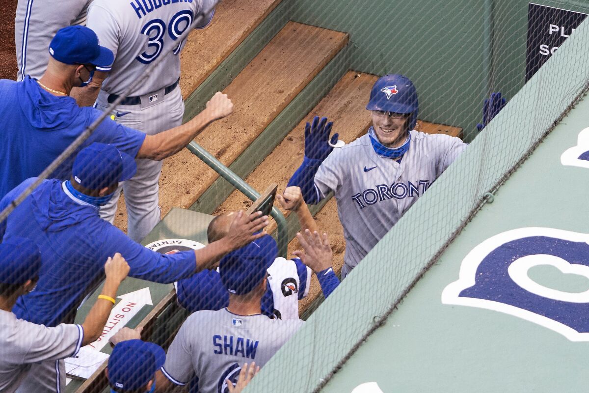 Toronto Blue Jays' Danny Jansen is congratulated by teammates in the dugout after his two-run home run against the Boston Red Sox during the second inning of the first game of a baseball doubleheader Friday, Sept. 4, 2020, at Fenway Park in Boston. (AP Photo/Winslow Townson)
