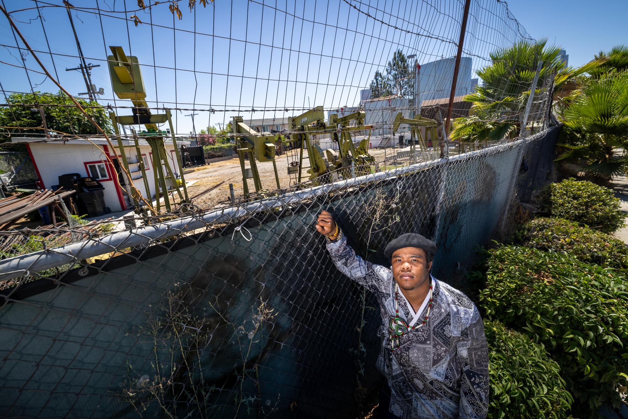 A student activist stands near oil pumps.