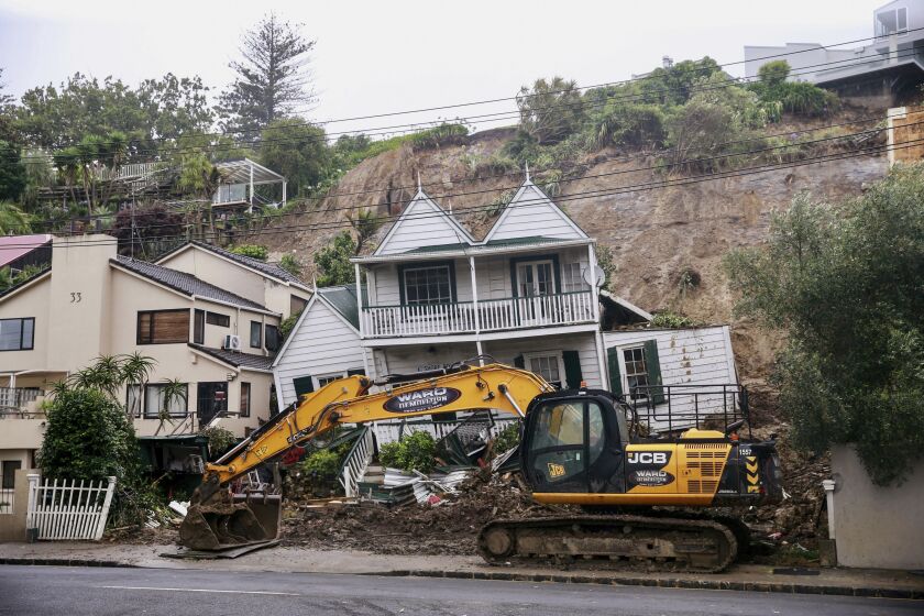 An excavator works at a home badly damaged by flooding and landslides in Auckland, New Zealand, Sunday, Jan. 29, 2023. A dangerous amount of rain is forecast Tuesday for New Zealand’s most populous city four days after Auckland had its wettest day on record in a storm that claimed four lives. (Alex Burton/New Zealand Herald via AP)