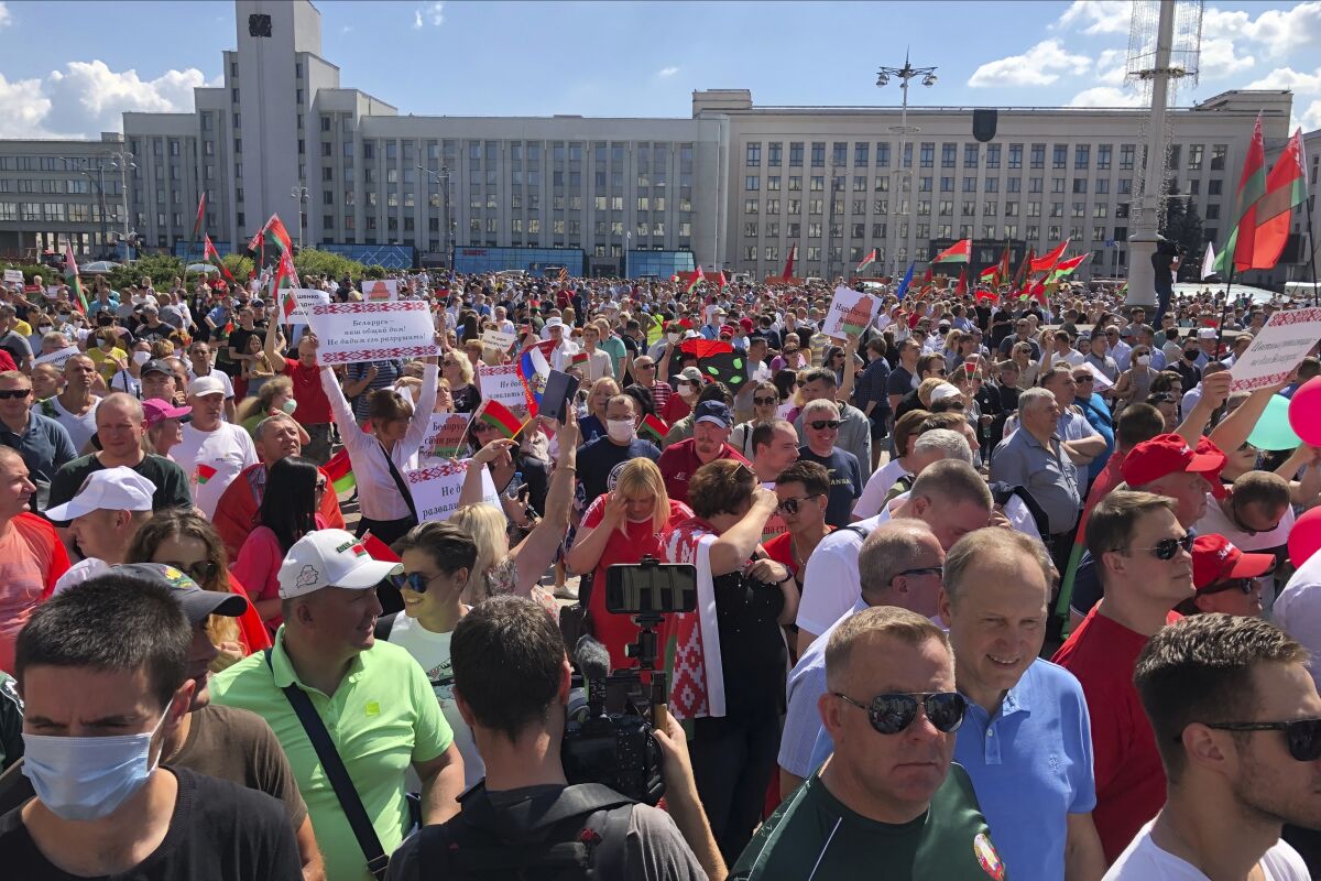 Hundreds of supporters of Belarusian President Alexander Lukashenko with Belarusian State flags, and a poster that reads: "Our President, our Country!, Not let destroy the country", gather at Independent Square of Minsk, Belarus, Sunday, Aug. 16, 2020. On Saturday, thousands of demonstrators rallied at the spot in Belarus' capital where a protester died in clashes with police, calling for Lukashenko to resign. (AP Photo/Sergei Grits)