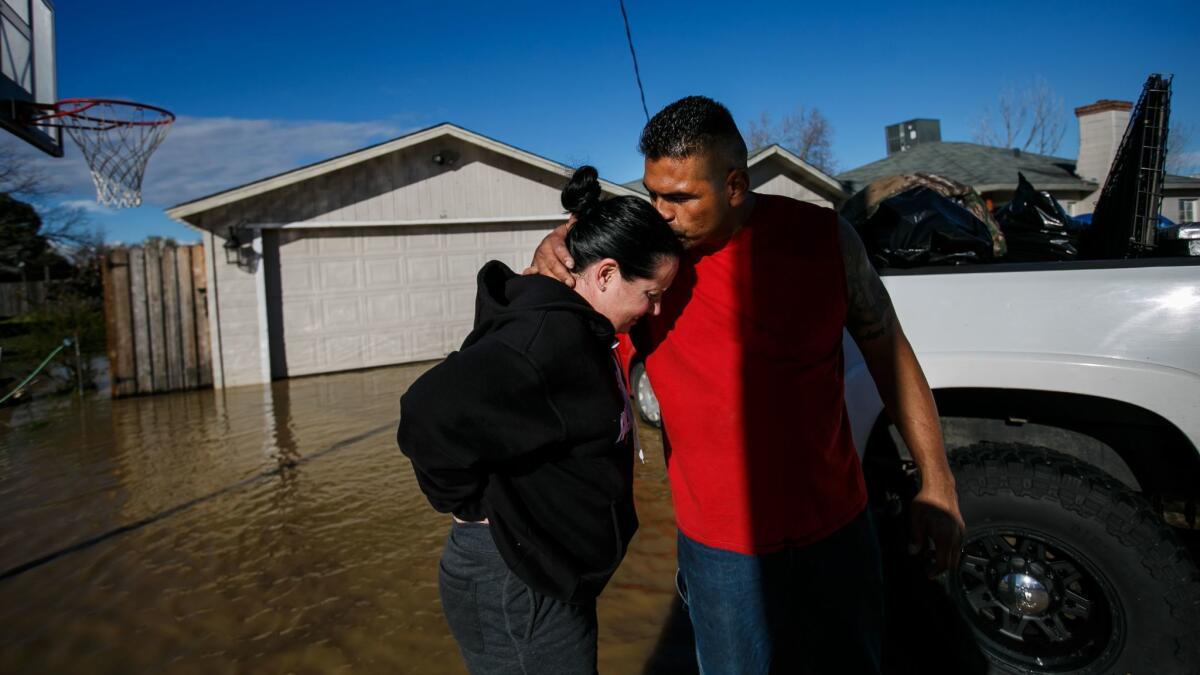 Juan Álvarez reconforta a su novia, Sarah Hendrix, luego de ayudarla a mudarse de su casa inundada en Maxwell, California (Marcus Yam / Los Angeles Times).