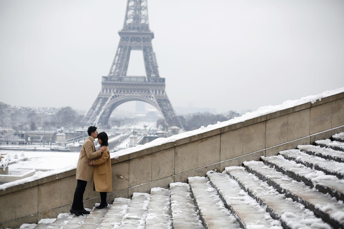 Una pareja de turistas se besa frente a la Torre Eiffel, cerrada por mal clima. Los visitantes tuvieron que conformarse con ver la torre de hierro blanqueada por nieve desde los jardines cercanos al monumento en París.