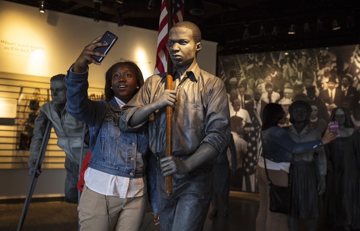 Imani Washington, 13, of Atlanta, takes a selfie with a bronze statue of civil rights marcher Timothy Mays at the Lowndes County Interpretive Center on the Selma to Montgomery National Historic Trail.