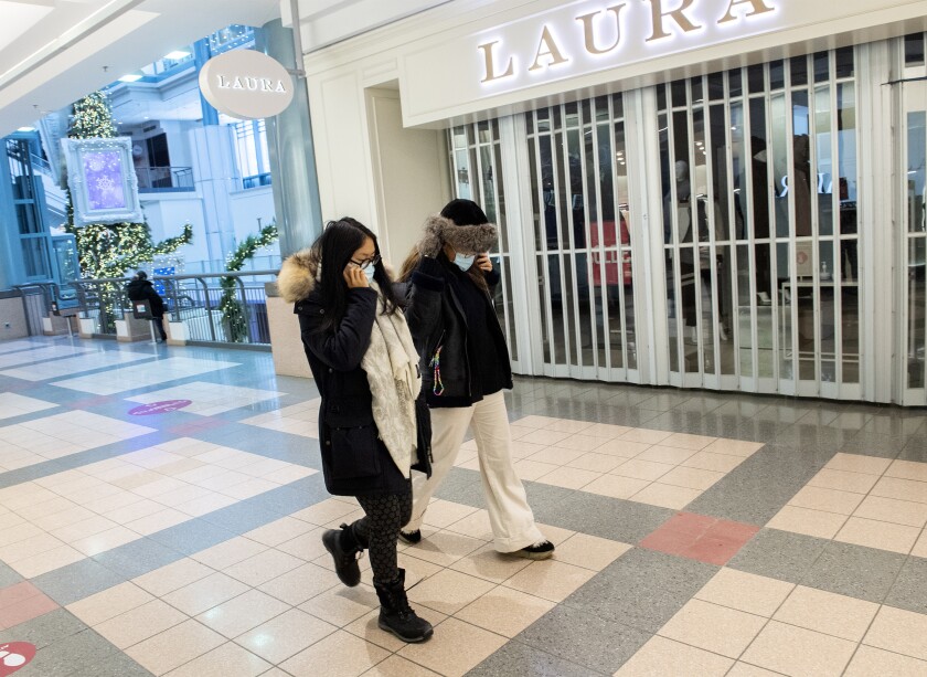 People walk by a closed store in a mall in Montreal, Sunday, Jan. 2, 2022, as the COVID-19 pandemic continues in Canada. Some measures put in place by the Quebec government, including the closure of stores, go into effect today to help curb the spread of COVID-19 in the province. (Graham Hughes /The Canadian Press via AP)
