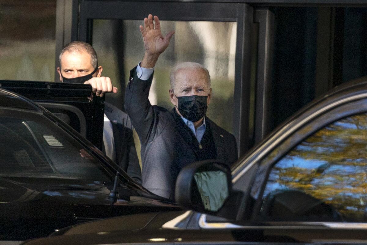 President Biden waves as he gets out of a car.