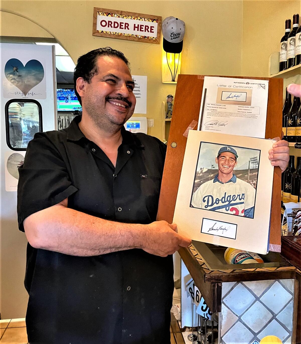 Juan Gomez holds up a portrait of Dodgers great Sandy Koufax in his restaurant Penne Pasta in Lehaina, Hawaii