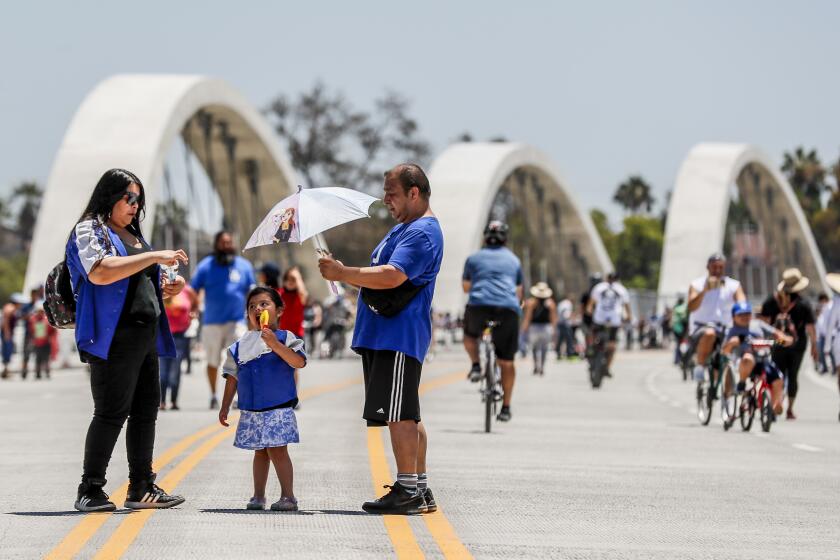 Los Angeles, CA, Sunday, July 10, 2022 - Violet Martinez, 3, enjoys a frozen treat as her uncle Claudio Martinez and mother Daisy Martinez stand by while trekking the Sixth Street Viaduct, downtown. (Robert Gauthier/Los Angeles Times)
