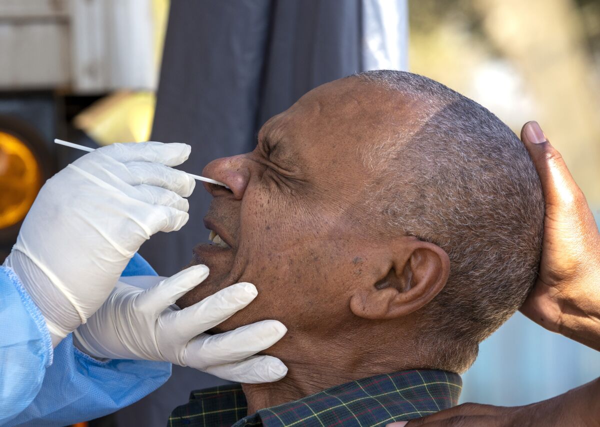 A man reacts as a health worker collects a sample for coronavirus testing during the screening and testing campaign aimed to combat the spread of COVID-19, in Eldorado Park outside of Johannesburg, South Africa, Monday, Aug. 3, 2020. (AP Photo/Themba Hadebe)