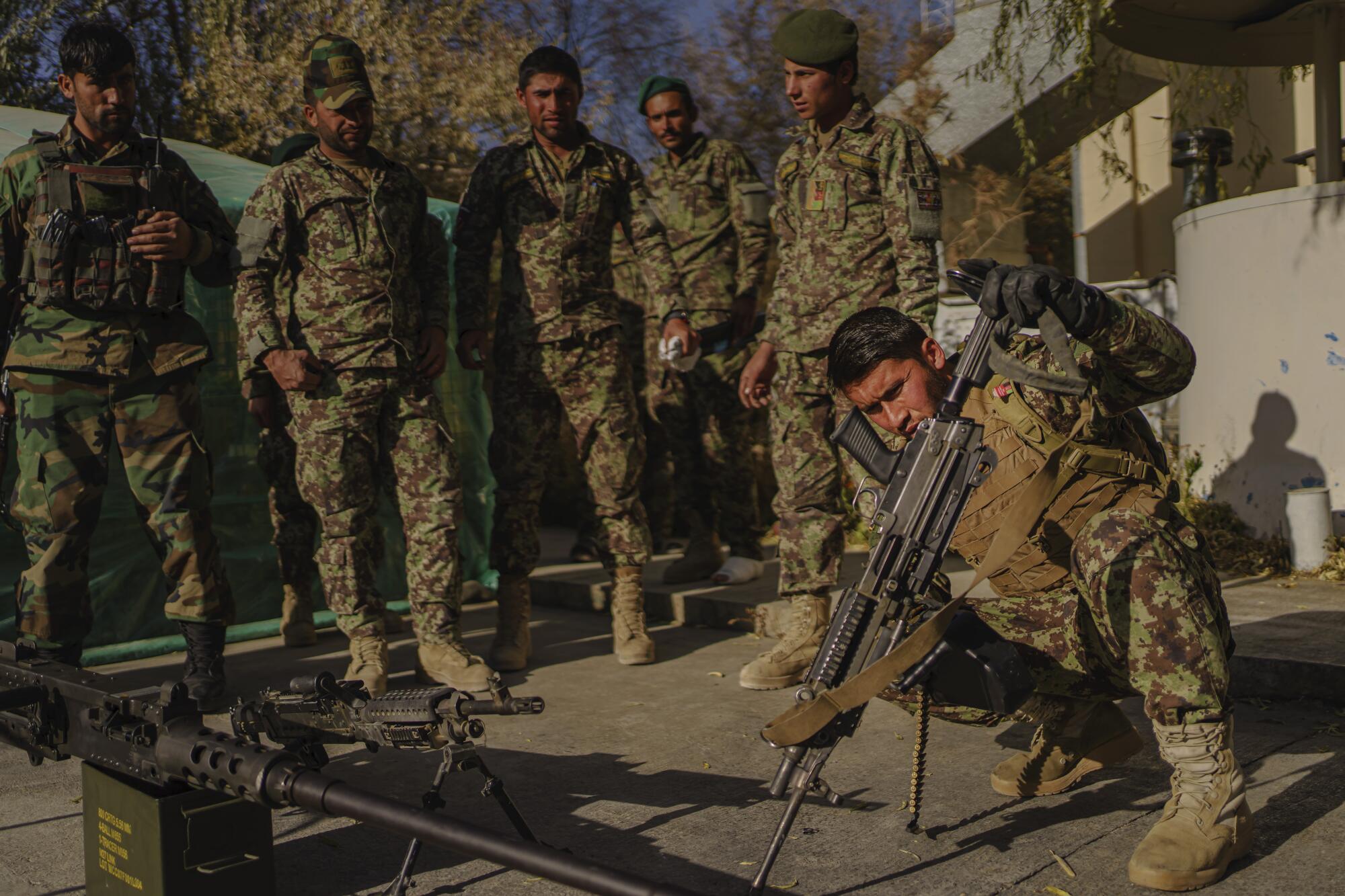 Soldiers inspect and clean their weapons.