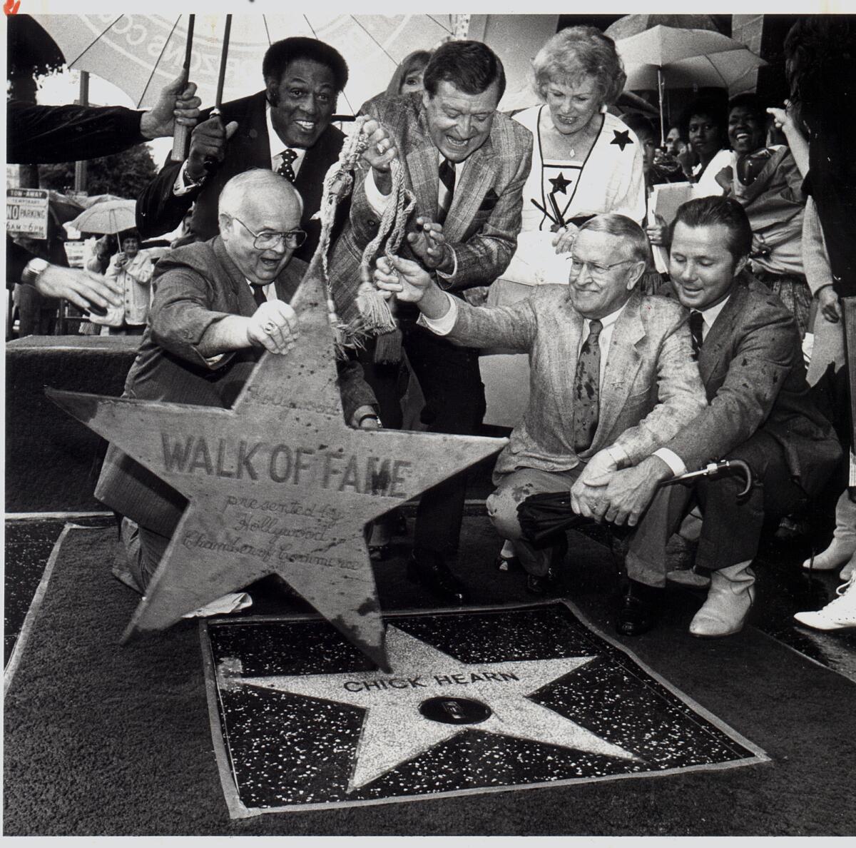 Laker announcer Chick Hearn gets an assist from honorary Hollywood mayor Johnny Grant while unveiling star on Walk of Fame.