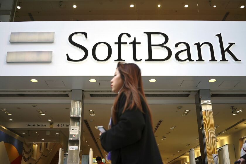 A woman walks in front of SoftBank store in Ginza shopping district in Tokyo, Jan. 20, 2020. Japanese investor SoftBank Group reported Tuesday, Feb. 7, 2023 that it sank into a deep loss for the October-December quarter, slammed by the global plunge in technology shares. (AP Photo/Eugene Hoshiko)