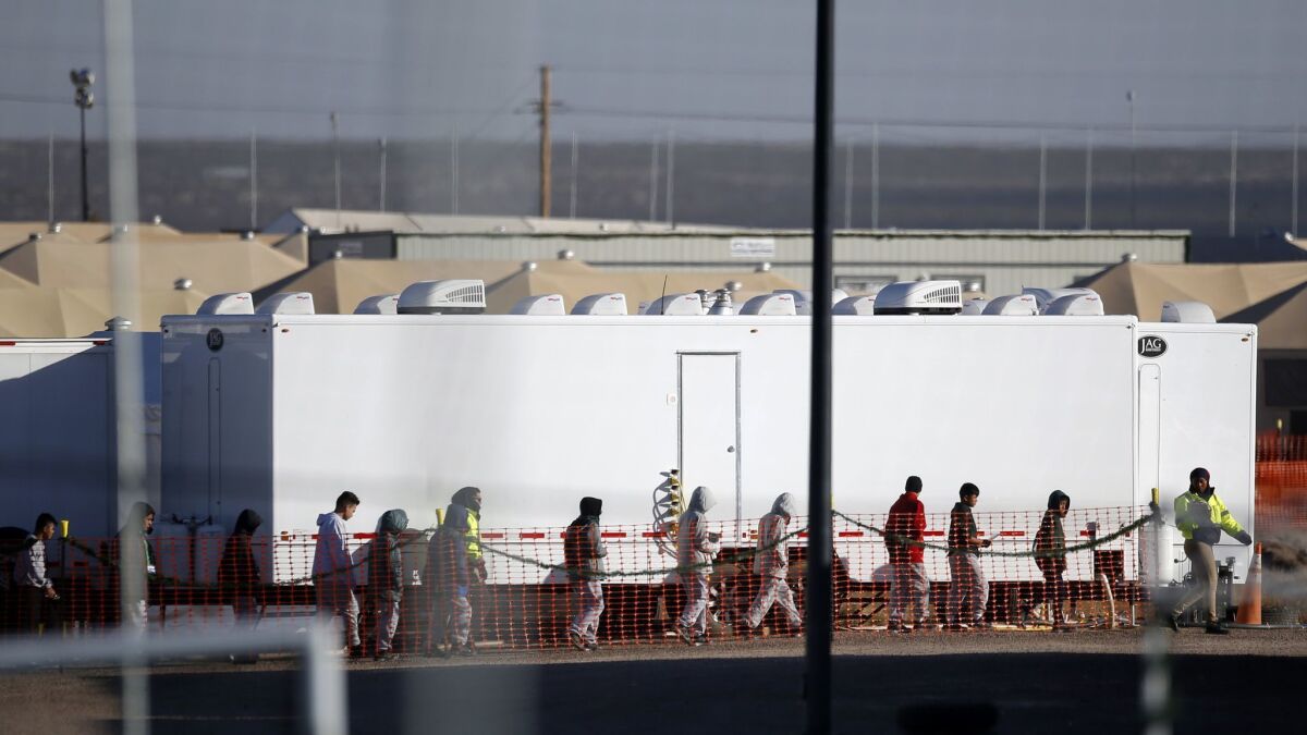 Migrant teens walk in a line through the tent camp in Tornillo, Texas, on Dec. 13.