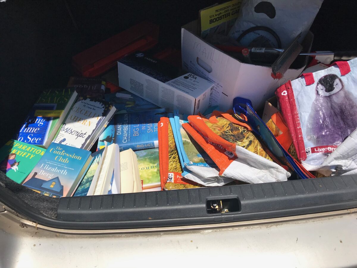 Inga's car trunk is seen filled with unreturnable library books, unrecyclable printer cartridges and unusable shopping bags.