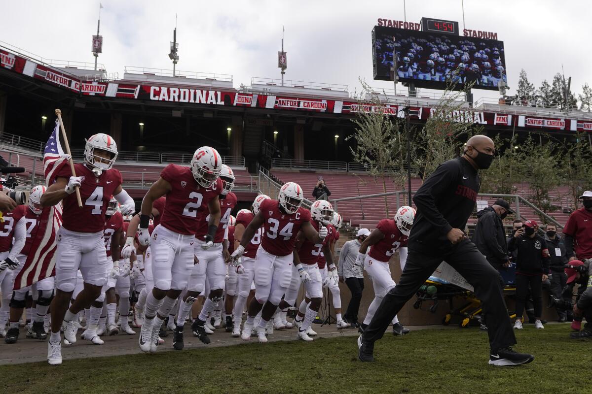 Stanford football players follow head coach David Shaw onto the field.