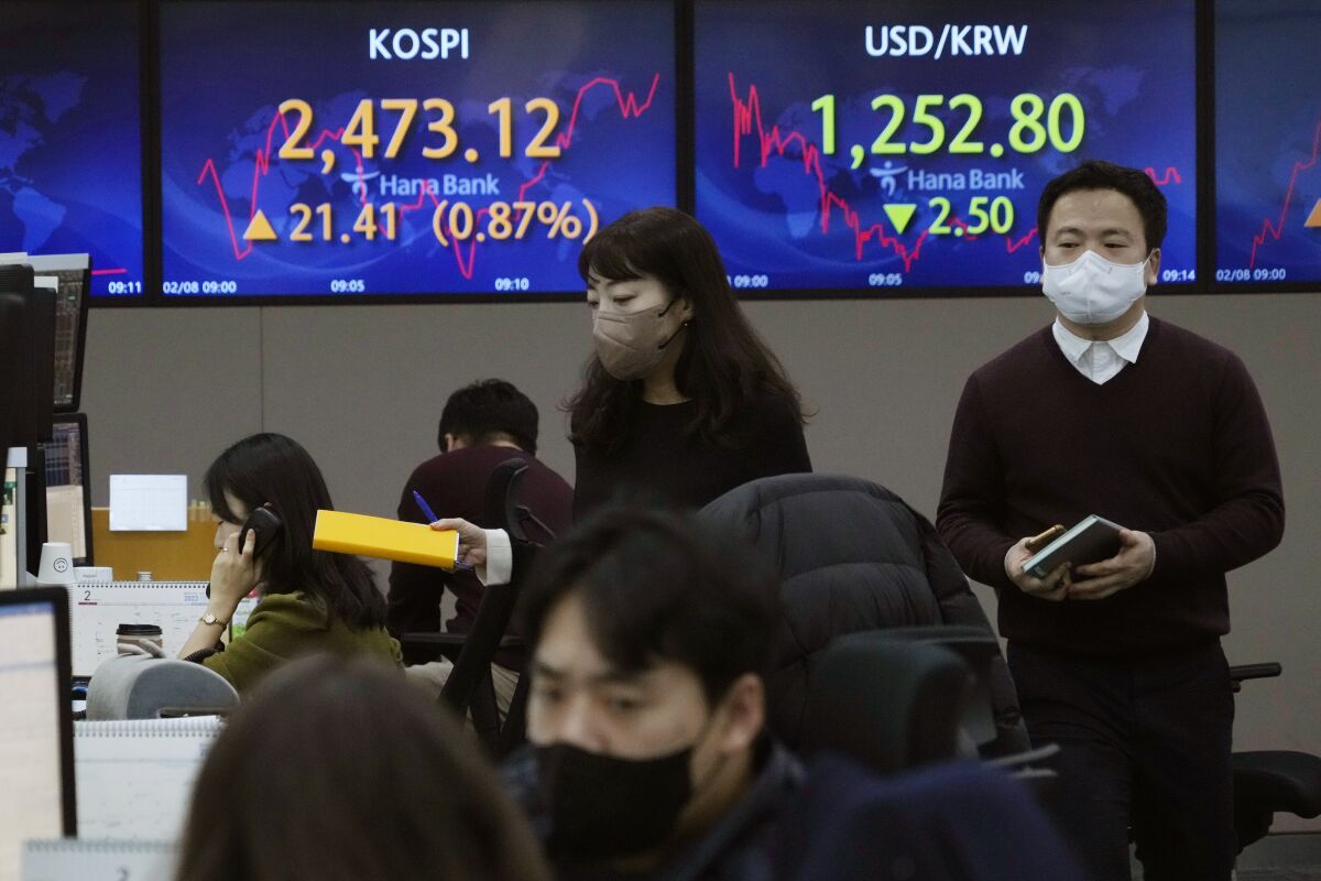 Currency traders pass by the screens showing the Korea Composite Stock Price Index (KOSPI), left, and the foreign exchange rate between U.S. dollar and South Korean won at the foreign exchange dealing room of the KEB Hana Bank headquarters in Seoul, South Korea, Wednesday, Feb. 8, 2023. Shares were mixed in Asia on Wednesday after stocks rallied on Wall Street following comments by the chair of the Federal Reserve signaling that last week’s stunningly strong jobs report won’t by itself sway its stance on interest rates hikes. (AP Photo/Ahn Young-joon)