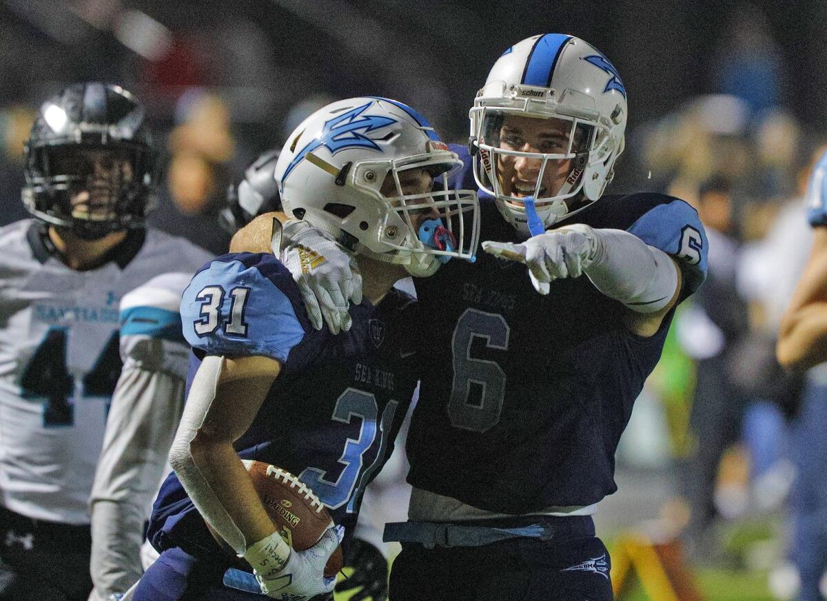 Riley Binnquist, left, and Corona del Mar teammate John Humphreys celebrate after Binnquist scores a touchdown against Santiago in the first round of the CIF Southern Section Division 3 playoffs on Friday at Newport Harbor High.