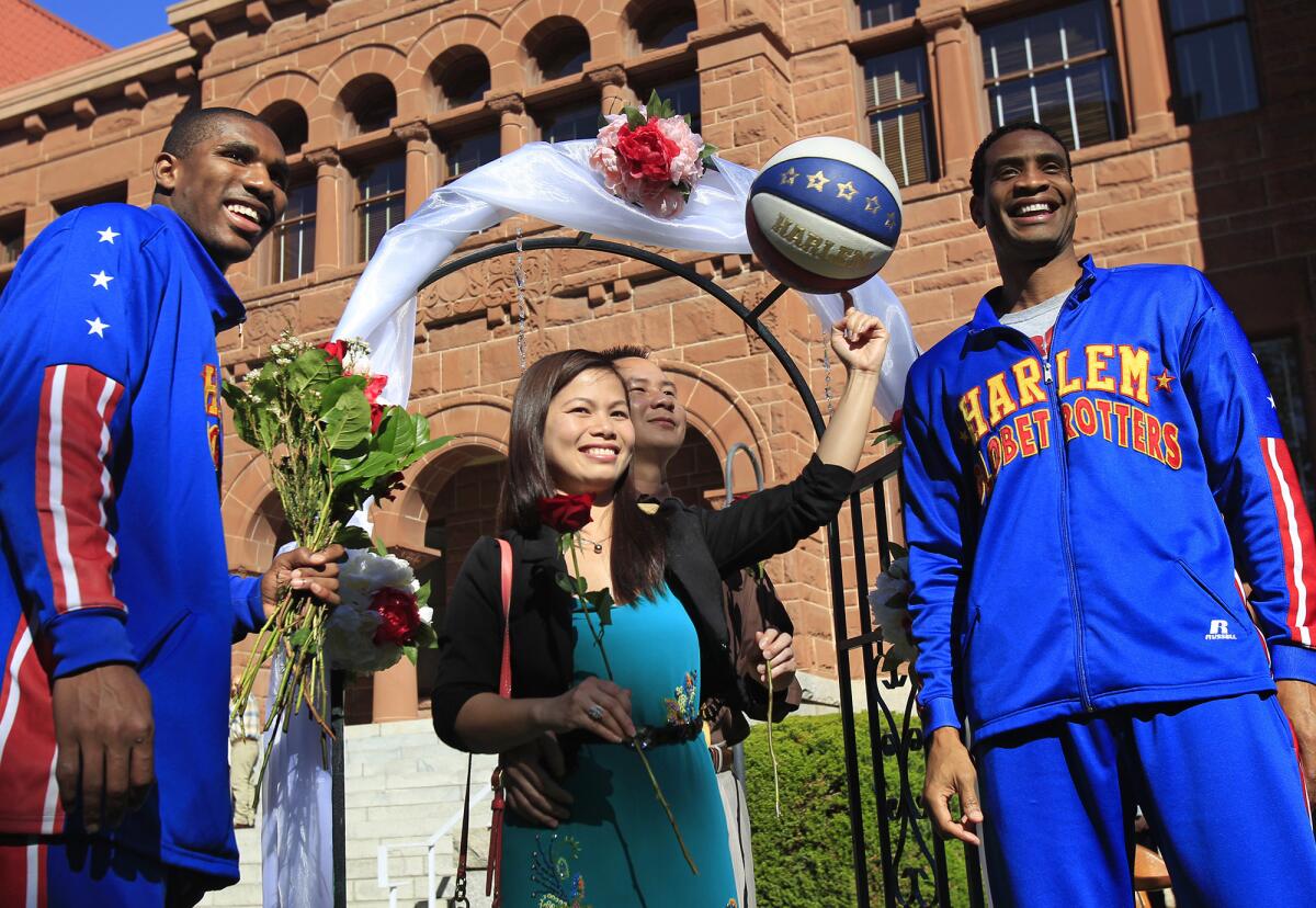 Harlem Globetrotters' Wun "The Shot" Versher, far right, and Corey "Thunder" Law, far left, pose for photos with couple Michelle Doan, 31, center, and Binh Nguyen, 39, center right, after they were married on Valentine's Day at the Old Orange County Courthouse in Santa Ana.