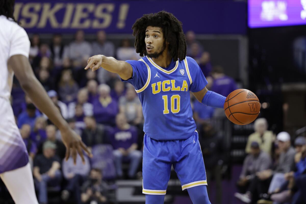 UCLA guard Tyger Campbell points to a teammate while dribbling the ball.