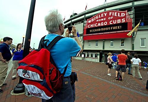 Jack Ness of St. Paul, Minn., takes a photo outside Wrigley Field in Chicago during the first stop of his Jay Buckley baseball bus tour.