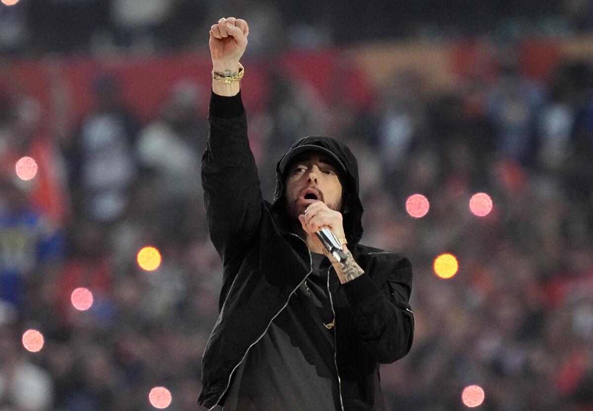 Eminem performing while wearing a black hoodie and raising a first in the air