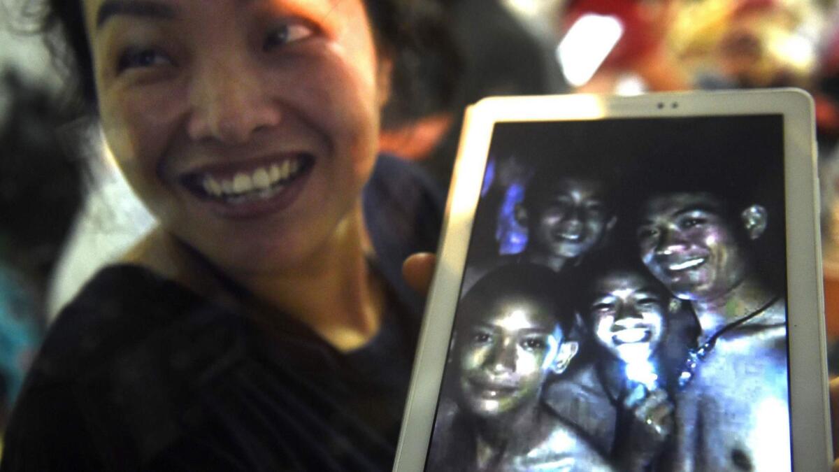 A relative shows a picture of the missing boys found by rescue divers inside a cave in Thailand.