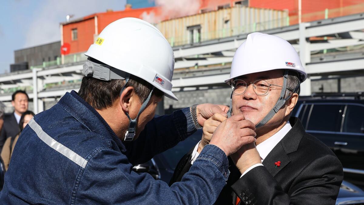 South Korean President Moon Jae-in, right, puts on a safety helmet during his tour of a hydrogen plant in Ulsan, South Korea. Critics have pointed to the lackluster economy to say the president should be focusing on bettering South Korean lives, engaging with North Korea.
