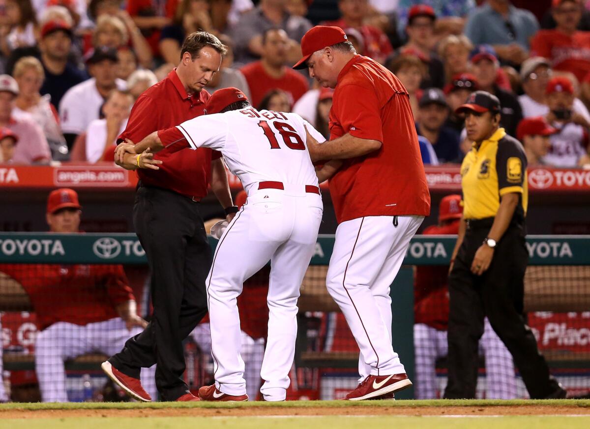 Angels Manager Mike Scioscia, right, and trainer Adam Nevala tend to pitcher Huston Street during the ninth inning against Seattle on Saturday night.